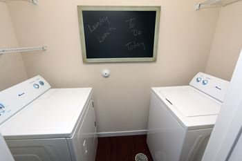 a laundry room with two washers and a chalkboard on the wall  at Aventura at Richmond, St. Peters, MO, 63376
